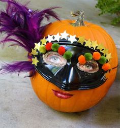 a pumpkin with a face painted to look like a person wearing a mask and feathers