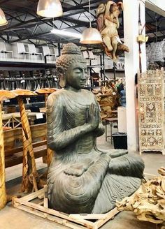 a buddha statue sitting on top of a wooden pallet in a room filled with other items