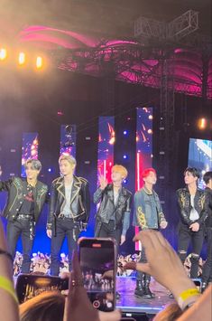 a group of young men standing on top of a stage with their hands in the air