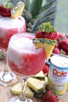 two glasses filled with fruit and ice cream next to pineapples on a table