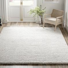 a large white rug in the corner of a room with a chair and potted plant