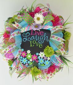 a colorful wreath with the words live laugh love written on it and flowers in front