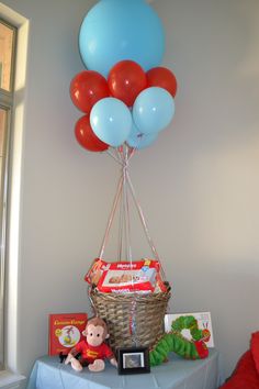 a basket with balloons and stuffed animals on a table