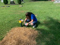 a woman kneeling down next to a pile of hay