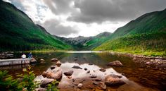 a lake surrounded by green mountains and rocks