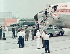 an airplane with people standing around it on the tarmac