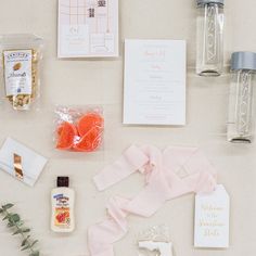 the contents of a wedding stationery laid out on a white surface with pink ribbon