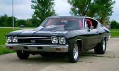 an old muscle car parked in a driveway