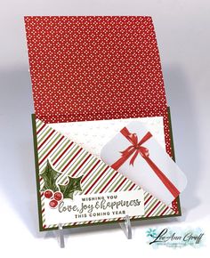 a close up of a christmas card with a gift box on the front and an envelope that says wishing you love, joy, happiness