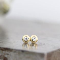 These two 14k yellow gold stud earrings are tiny and perfect for everyday wear. They feature sparkly 2mm moissanite gemstones set into solid gold (not hollow) lenti-shaped studs. These recycled, diamond alternative studs are ready to ship. These are the perfect every day earrings with just the right amount of flash. They would be great in a second piercing or as a barely-there, never-take-'em-off stud in your regular piercing. This listing is for a pair of earrings.These earrings measure 4mm acr Minimalist Yellow Gold Diamond Earrings For Anniversary, Minimalist Round Cut Gold Earrings, Gold Diamond Earrings Brilliant Cut Minimalist Style, Gold Minimalist Diamond Earrings With Brilliant Cut, Gold Minimalist Brilliant Cut Diamond Earrings, Minimalist Gold Earrings With Brilliant Cut, Everyday Yellow Gold Earrings With Single Diamond, Minimalist Yellow Gold Earrings With Vvs Clarity, Minimalist Bezel Set Earrings For Anniversary