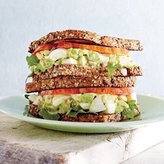 a sandwich with lettuce, tomato and other vegetables on it sitting on a plate