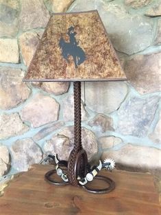 a lamp that is sitting on top of a wooden table in front of a stone wall