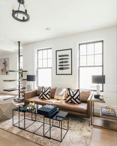 a living room with couches, tables and lamps on the floor in front of windows