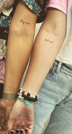 two people holding hands with small tattoos on their arms and the words love are written in cursive letters