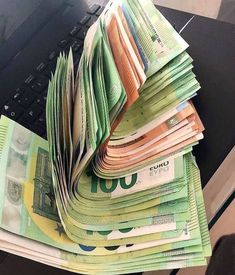 a pile of money sitting on top of a laptop computer