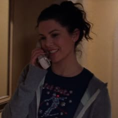 a woman talking on a cell phone while standing in front of a mirror and smiling