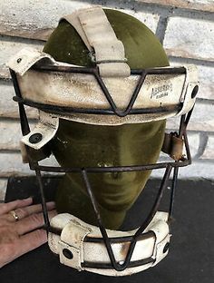 an old baseball helmet is being held up by a person's hand on a table