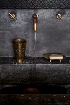 an image of two gold cups and a water faucet on a shelf with other items