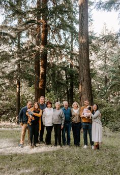 a group of people standing next to each other in front of some tall pine trees