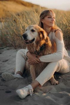 a woman sitting in the sand with her dog