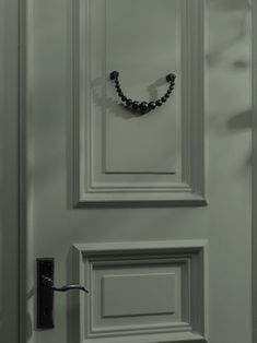 a door with a black beaded necklace hanging on it's front door handle