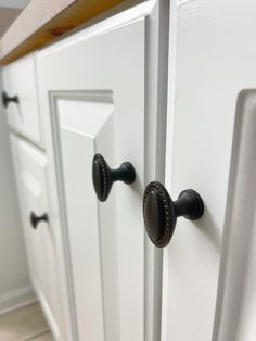 a white cabinet with black handles and knobs on the door handle is seen in this image