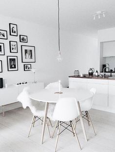 a white table and chairs in a room with pictures on the wall behind it,