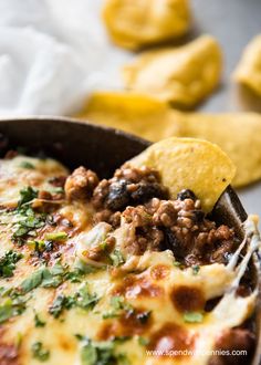 a close up of a spoon in a casserole with meat and cheese on it