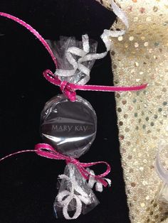 an ornament is wrapped in clear plastic and tied with pink ribbon on a black velvet surface