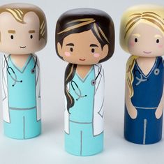 three wooden dolls are standing next to each other in the shape of people wearing scrubs