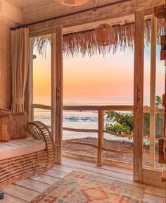 a room with a couch, chair and window overlooking the ocean at sunset or sunrise