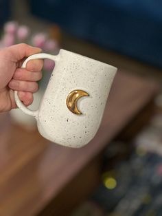 a person holding a coffee cup with a crescent decoration on the side and a gold ring in the middle