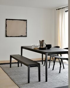 a dining room table with two benches in front of it and a painting on the wall