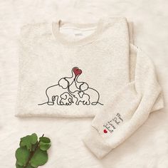 two sweaters sitting on top of a bed next to a plant and a potted plant