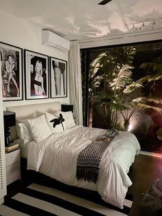 a bedroom with pictures on the wall above the bed and below the bed is a black and white striped rug