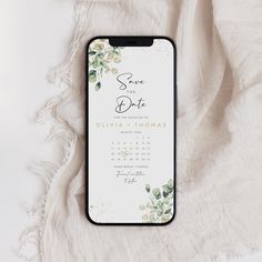 an iphone case sitting on top of a white blanket next to a flowered cloth