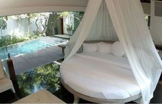 a white bed sitting under a canopy next to a swimming pool