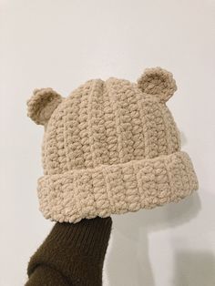 a person wearing a knitted bear hat on their head and mittens in front of a white wall