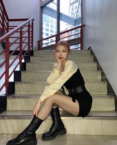 a woman sitting on some steps with her legs crossed and wearing black boots, tights and fishnet stockings