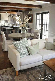 a living room filled with furniture next to a kitchen and dining room table in front of a window