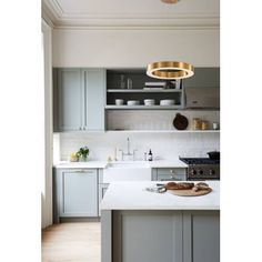 a kitchen with white counter tops and gold accents on the light fixture over the island