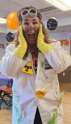 a woman wearing goggles and holding her hands up to her face while standing in front of balloons