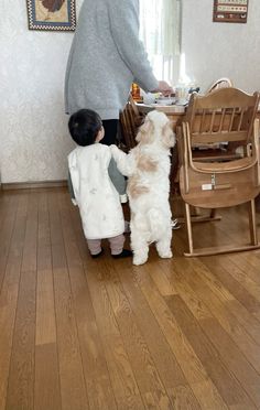 a woman standing next to a little boy in a kitchen with a dog on the floor