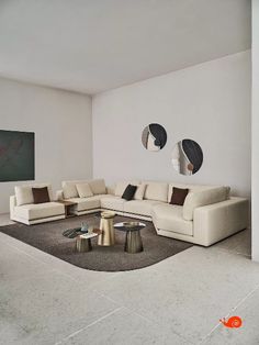 a living room filled with furniture next to a white wall and two round mirrors on the wall