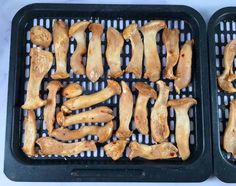 two black trays filled with chicken wings on top of a white countertop next to each other