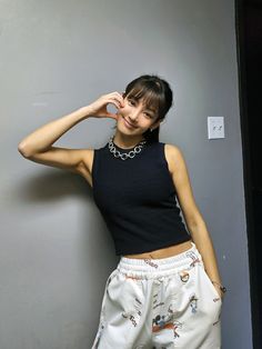 a woman in black top and white shorts posing for the camera with her hand on her head