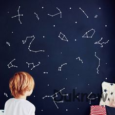 a little boy sitting in front of a wall with stars on it