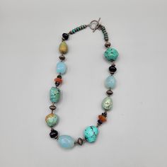 "Southwestern Boho mixed materials necklace with varied colors and sizes and textures. Smooth light blue glass beads, faceted orange colored beads, turquoise color dyed howlite, smooth round amethyst with alternating metal beads. Has a hang tag, but unknown maker to me. Excellent condition with no visible damage. Measurements: Length - 16\" A10D021522" Bohemian Adjustable Turquoise Necklace With Faceted Beads, Adjustable Artisan Turquoise Single Strand Necklace, Artisan Turquoise Necklace With Faceted Beads, Artisan Jewelry With Oval Faceted Beads, Artisan Turquoise Necklace With Gemstone Beads, Handmade Bohemian Toggle Necklace For Gift, Handmade Bohemian Toggle Necklace As Gift, Bohemian Multicolor Turquoise Necklace With Faceted Beads, Bohemian Turquoise Healing Necklace Single Strand