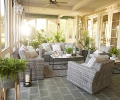 a living room with wicker furniture and potted plants on the porch area,