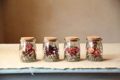 four jars with flowers in them sitting on a table